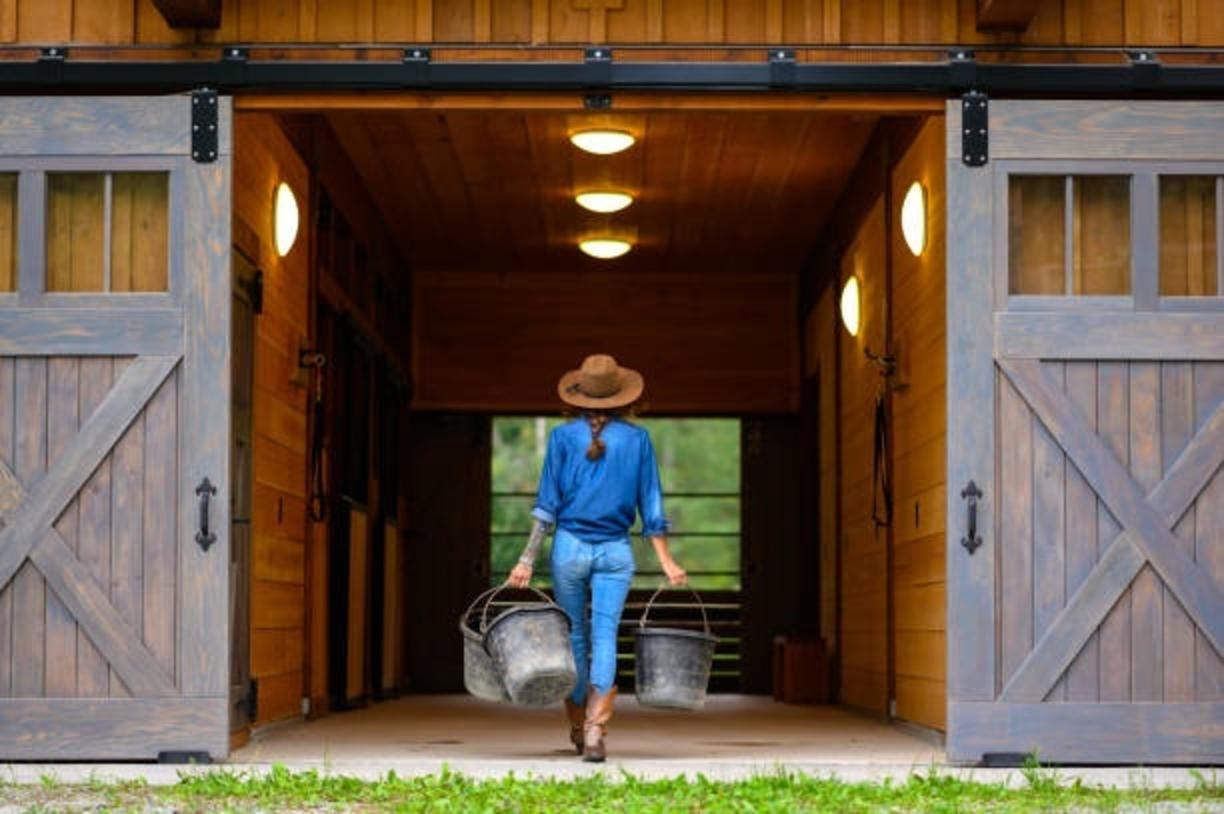 woman walking in barn with buckets